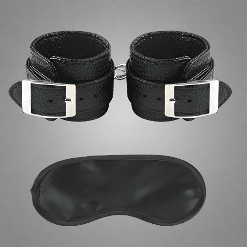 Black leather wrist cuffs and eye mask on a white background