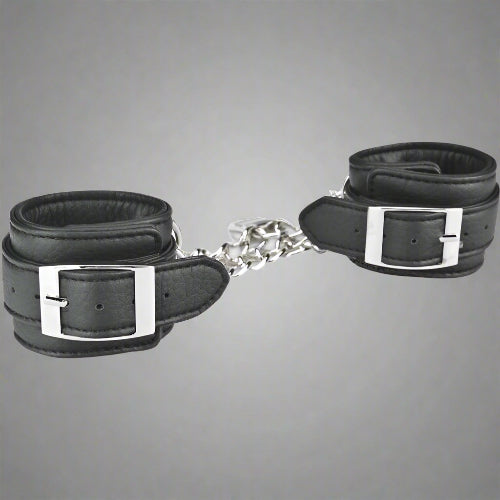 Black leather handcuffs with silver buckles on a white background
