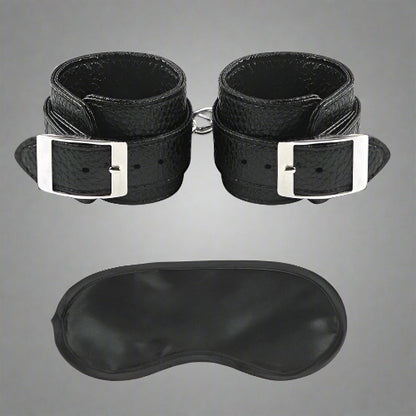 Black leather wrist cuffs and eye mask on a white background
