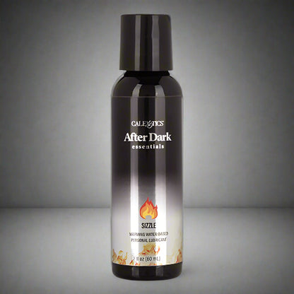 A black bottle of AFTER DARK WARMING LUBRICANT with a label showing the product name and a flame graphic, indicating a warming effect.