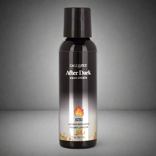 A black bottle of AFTER DARK WARMING LUBRICANT with a label showing the product name and a flame graphic, indicating a warming effect.